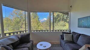 A cozy living room with a large window offering a mountain view, two sofas, and a small table.