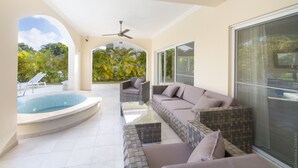 Une terrasse ensoleillée avec une piscine, un canapé et un ventilateur de plafond.