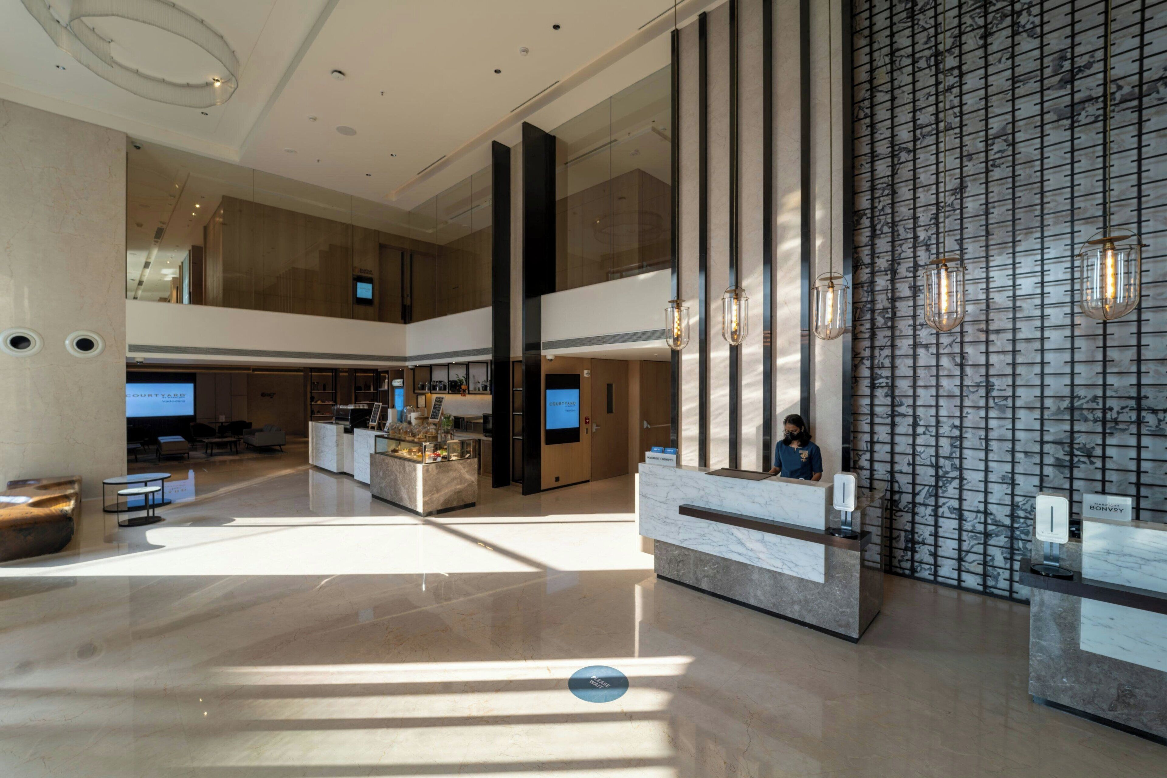 A spacious lobby with a high ceiling, a reception desk, and a seating area.