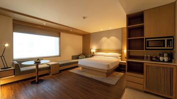 Una camera da letto moderna con un letto, comodini, un divano, un tavolino, un forno a microonde e un armadio.