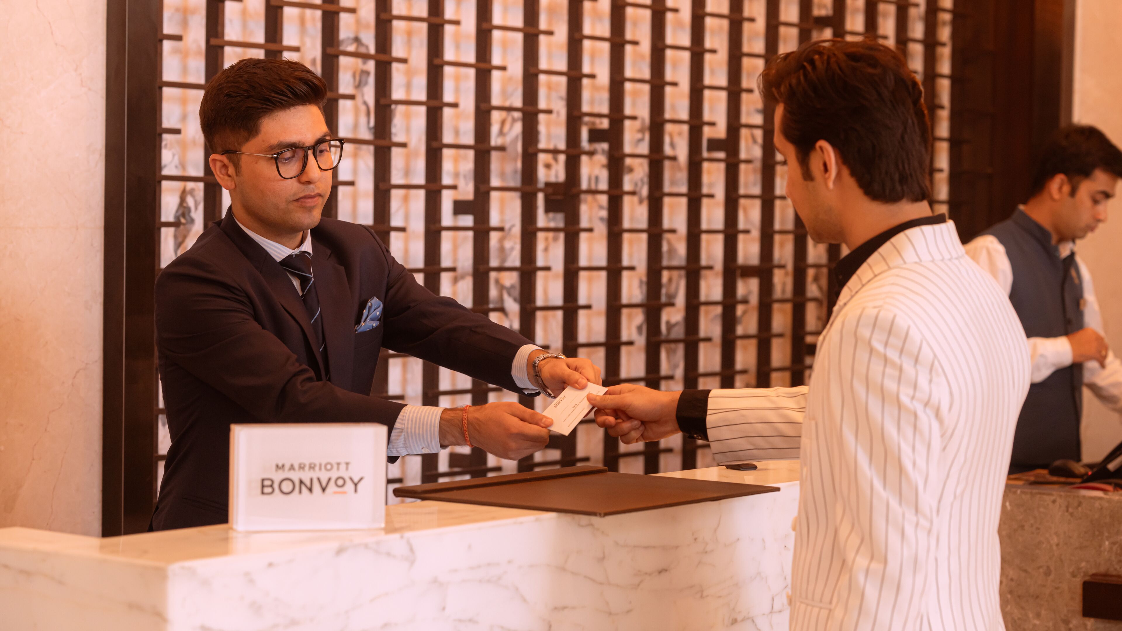 Un comptoir d’accueil avec une enseigne indiquant « Marriott Bonvoy » et un comptoir en marbre.