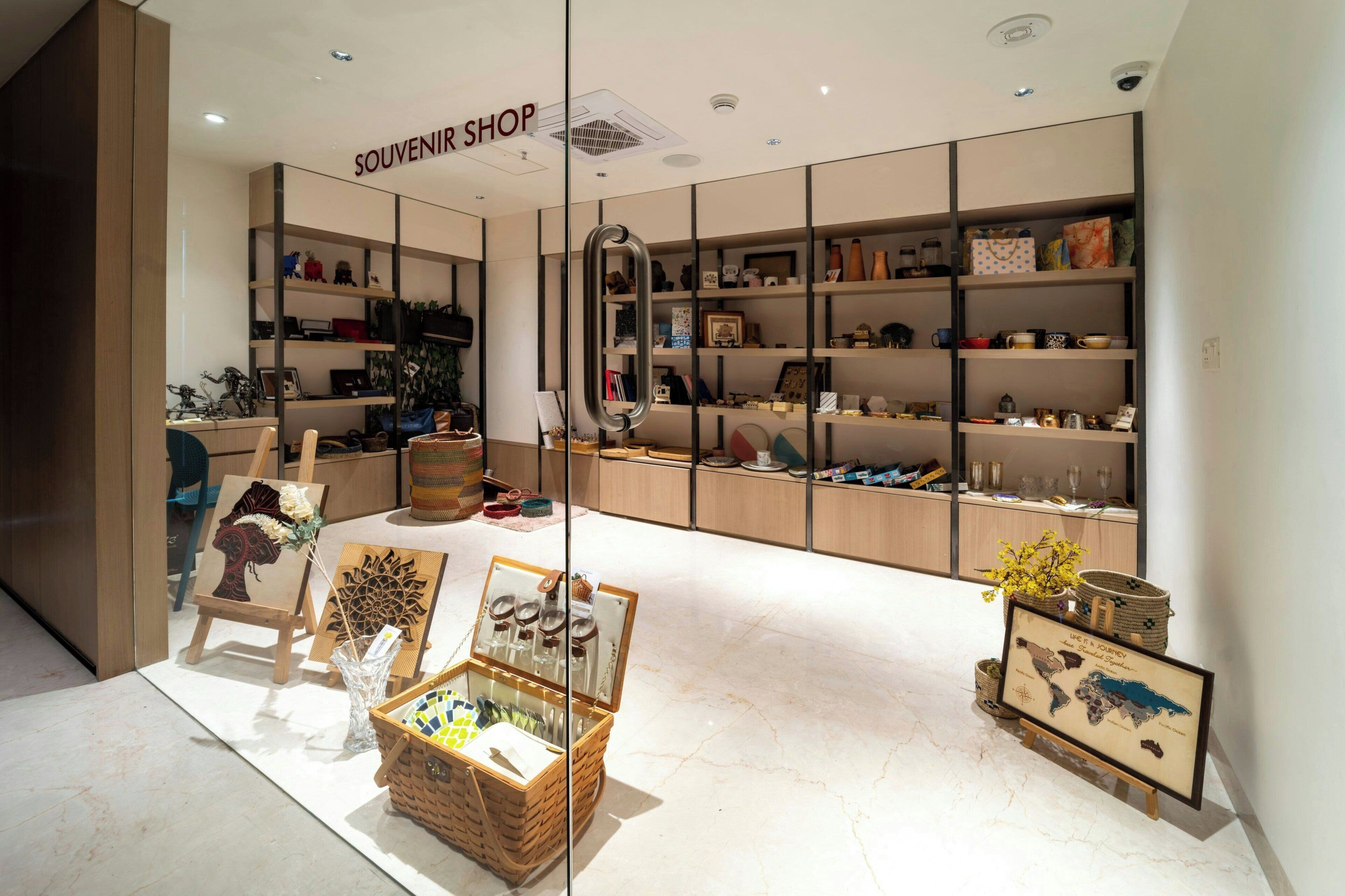 A souvenir shop with shelves of various items, a display of paintings, and a map.