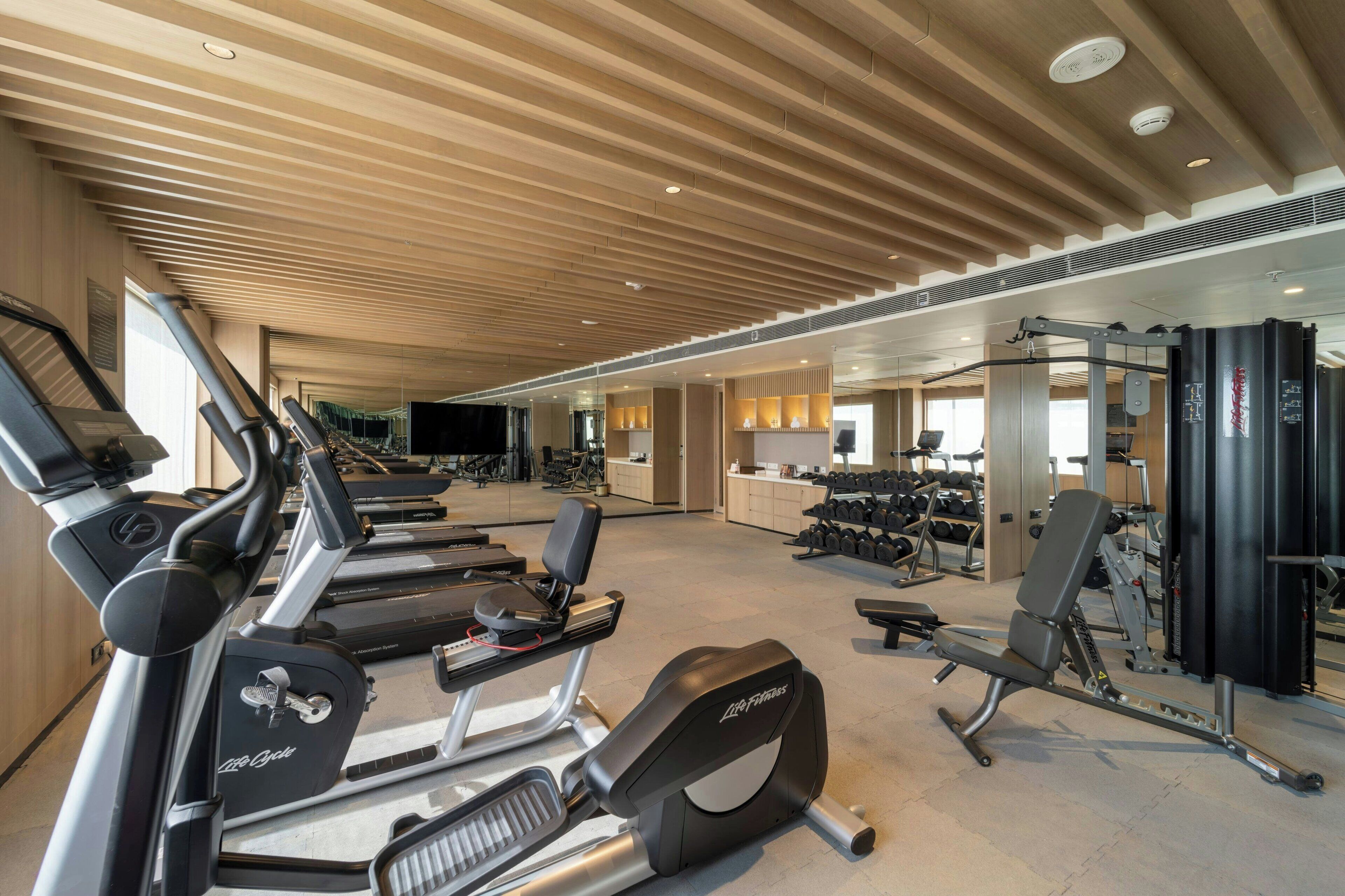 A gym with treadmills, weight machines, and dumbbells.