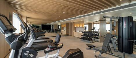 A gym with treadmills, weight machines, and dumbbells.
