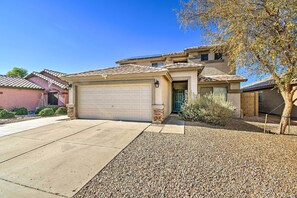 A two-story house with a garage, a stone accent wall, and a gravel driveway.