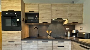 A modern kitchen with wooden cabinetry, a built-in oven, a microwave, and a coffee maker. - Apartment at the foot of the slopes - 4 guests (Les Belleville)