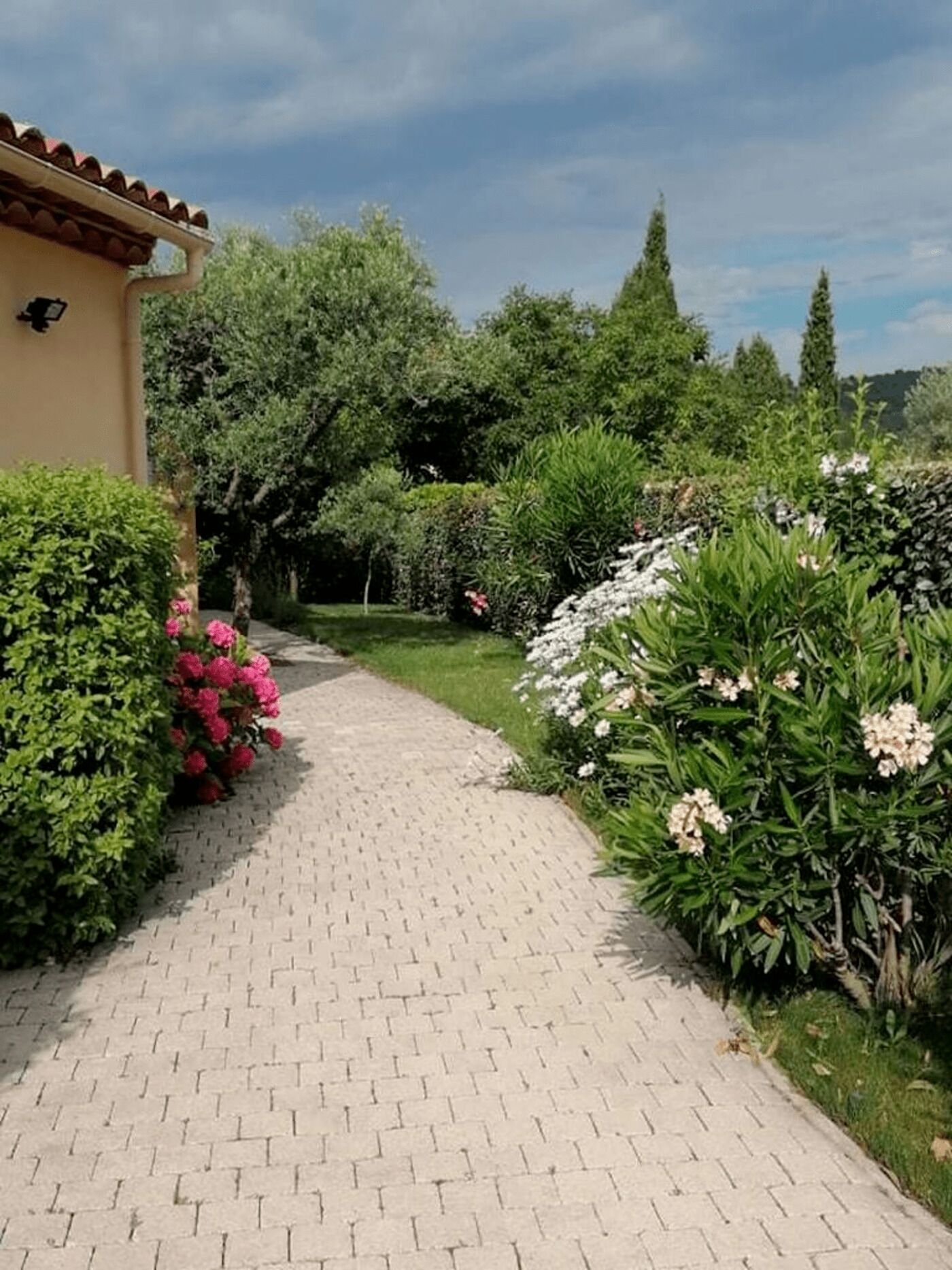 Ein gepflasterter Gartenweg führt zu einem Gebäude mit einem Ziegeldach.