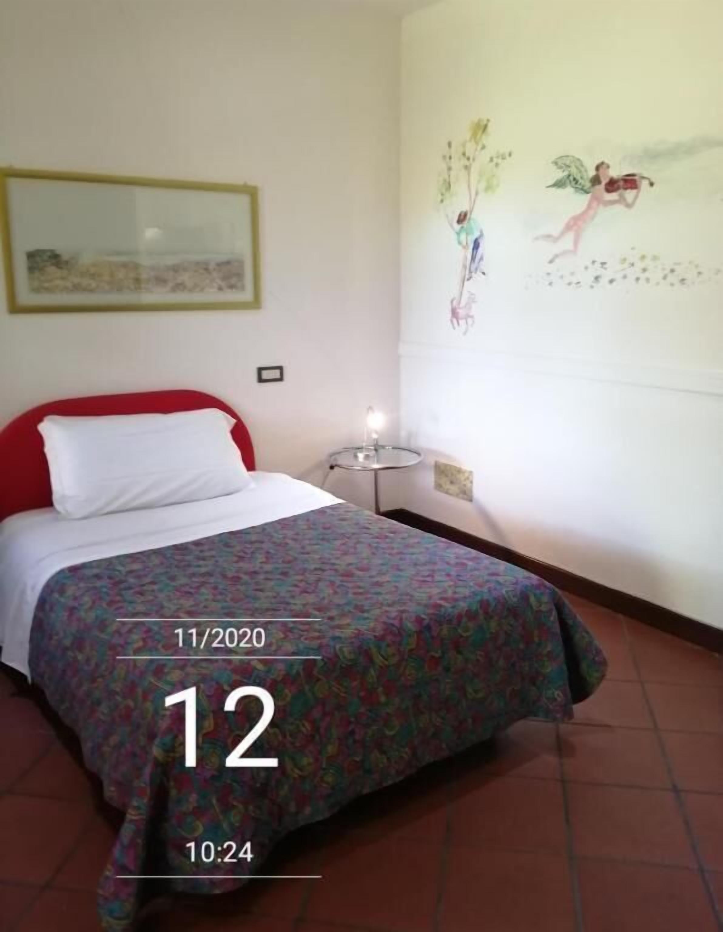 Una habitación de hotel con una cama, una mesita de noche con lámpara y una pared decorada con un mural.