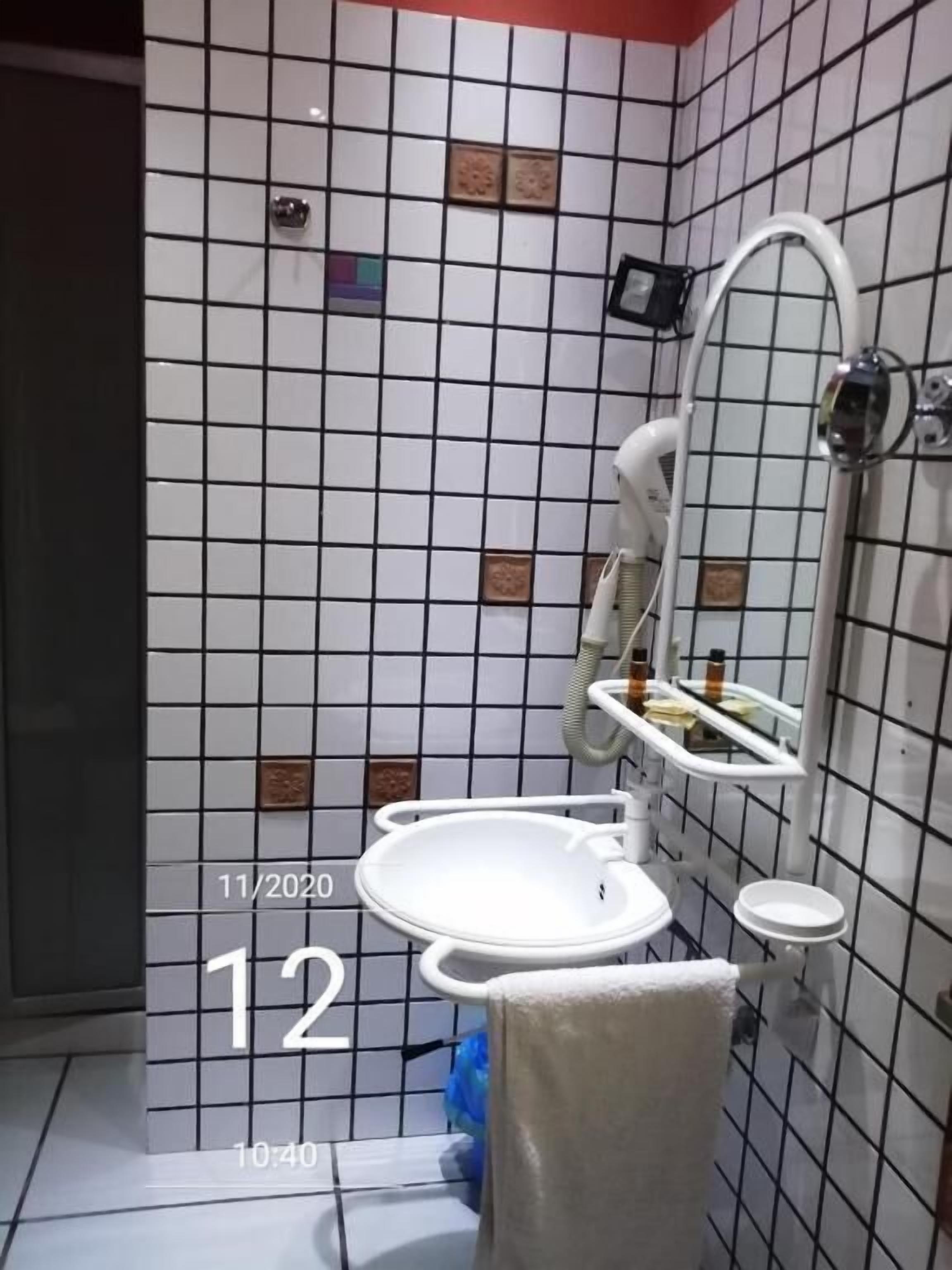 Een badkamer met een wit wastafel, spiegel en douchehoek.