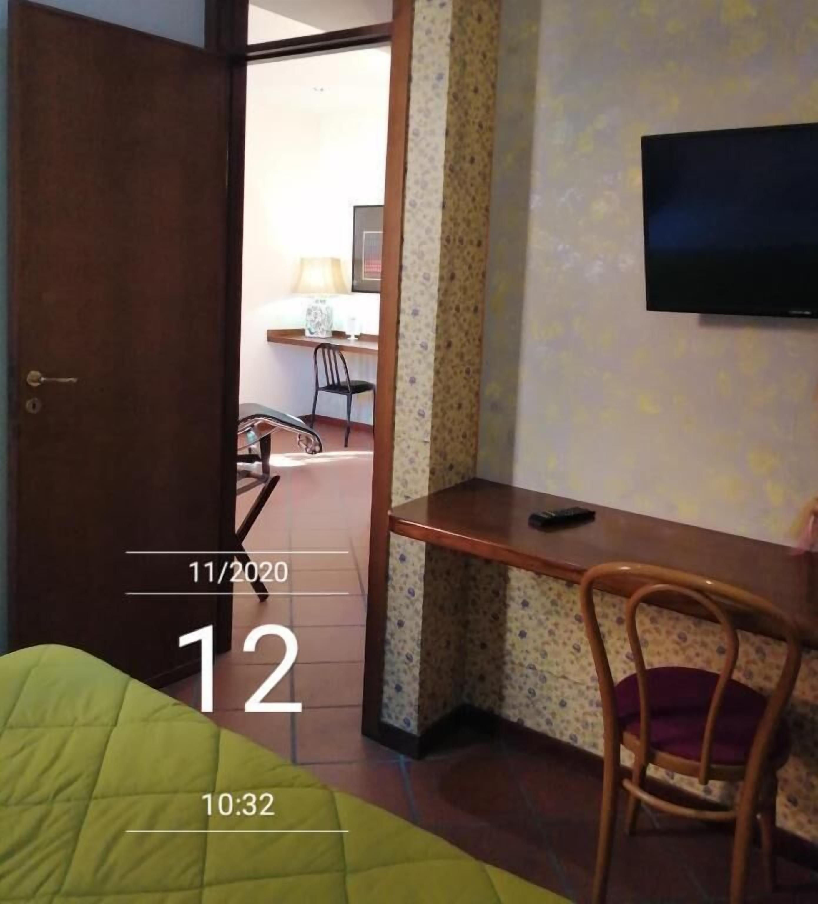 A hotel room with a bed, a desk, a chair, and a television on the wall.