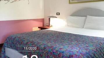 Ein Hotelzimmer mit einem Bett, einem Nachttisch, einer Wanduhr und einem Gemälde.