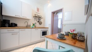 Une cuisine moderne avec des meubles blancs, un plan de travail en bois et un coin repas comprenant une table et des chaises.