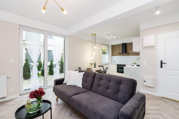 A cozy living room with a gray sofa, light wooden flooring, and modern decor.