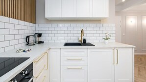 A modern kitchen with white cabinets, a black countertop, and gold handles. - Climatic Studio with Terrace | 500 m to the Old Town Square (Poznan)