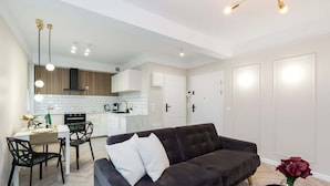 A modern living room with a dark sofa, a dining table with chairs, and a kitchen in the background. - Climatic Studio with Terrace | 500 m to the Old Town Square (Poznan)