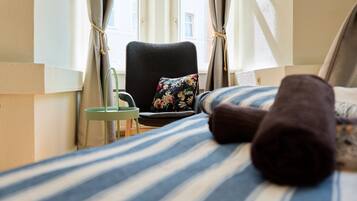 Ein Hotelzimmer mit einem Bett, einem Sessel, einem kleinen Tisch und Vorhängen.