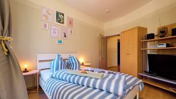 Quarto com cama, mesas de cabeceira, televisão e guarda-roupa.