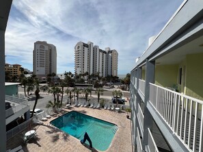 Hotel med pool, udendørs siddepladser og udsigt til høje bygninger og havet.