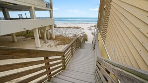 Una escalera de madera que conduce a una zona de playa con vistas al océano.