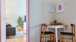 A dining area with a white table and two wooden chairs with black cushions. There are framed pictures on the wall and a plant on the table. - ★ Bright Jugendstil Apartment in the ❤ of Erfurt ★ (Erfurt)