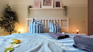 A neatly made bed with striped pillows, a bedside lamp, and a wall-mounted shelf with framed pictures and a plant. - ★ Bright Jugendstil Apartment in the ❤ of Erfurt ★ (Erfurt)