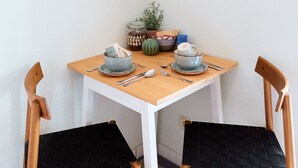 A small wooden table with two chairs, a bowl, a spoon, a fork, a knife, a jar, a potted plant, and a box of snacks. - ★ Bright Jugendstil Apartment in the ❤ of Erfurt ★ (Erfurt)