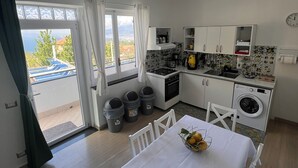 Kompakti keittiö, jossa on ruokailutila, pesukone ja näkymä ulos.