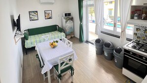 Kompakti oleskelutila, jossa on pieni keittiönurkkaus, ruokailualue ja sohva.