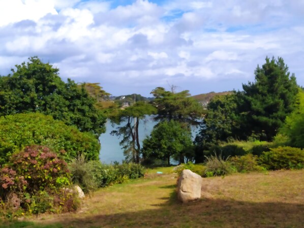 A natural landscape with a lake, dense greenery, and a clear sky.