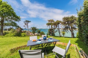 An outdoor dining area with a table set for two, overlooking a body of water and surrounded by trees.