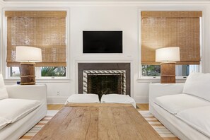 Cozy living room with a central fireplace, two sofas, and a flat-screen TV.
