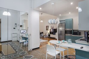 Eine moderne Küche mit Kühlschrank, Mikrowelle und Herd. Ein Essbereich mit Tisch und Stühlen ist vorhanden.