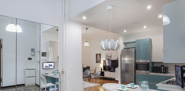 Une cuisine moderne avec un coin repas, équipée d’un espace de travail fonctionnel comprenant un ordinateur et un téléviseur.