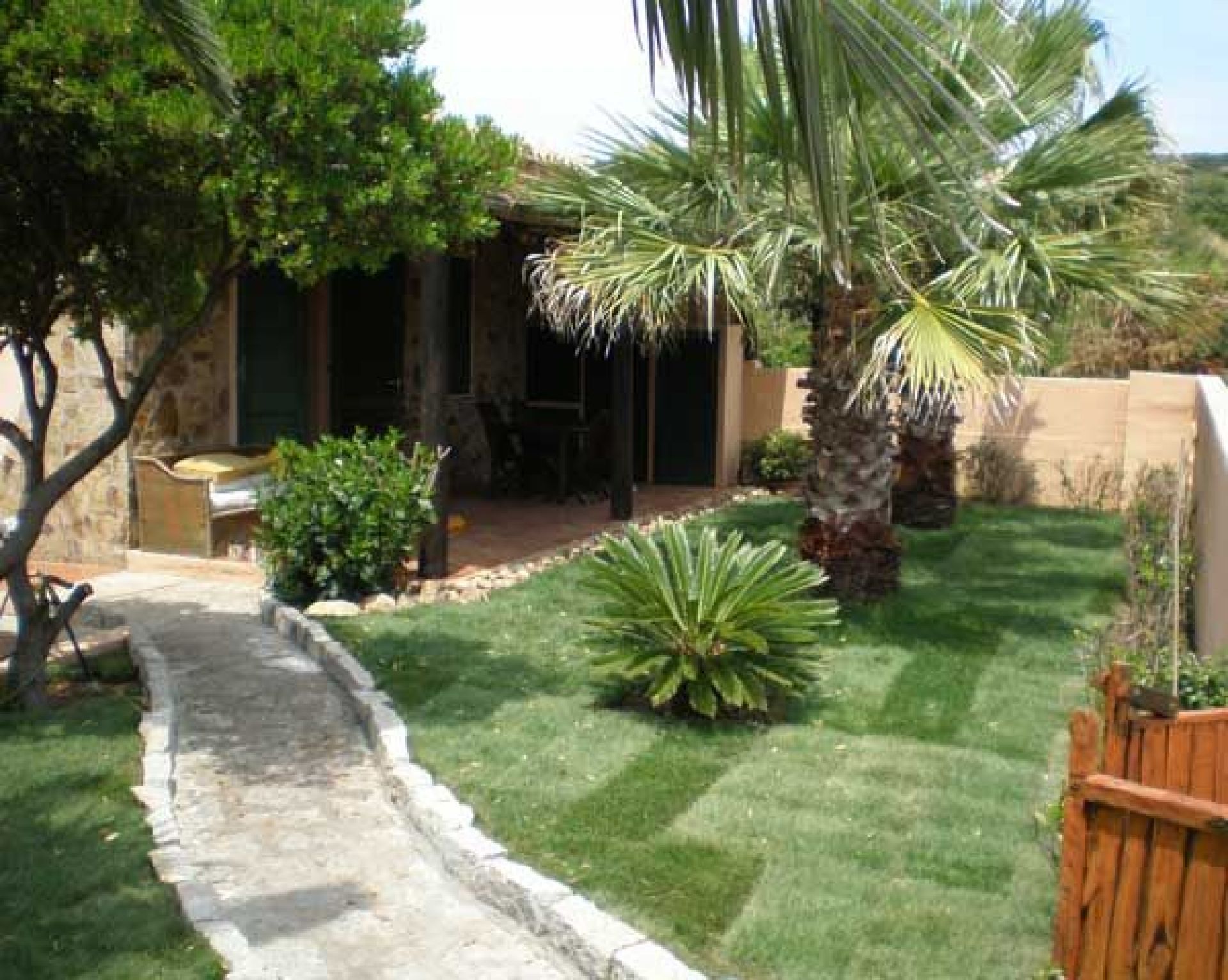 Un jardín cuidado con un sendero de piedra que lleva a un patio.