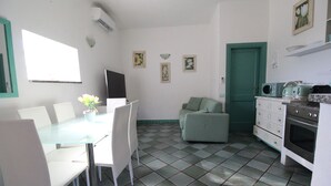 Une cuisine de taille réduite avec un coin repas, une porte verte et un sol carrelé.