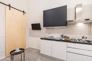 Een koelkast, een oven, een waterkoker, kookgerei, borden en bestek