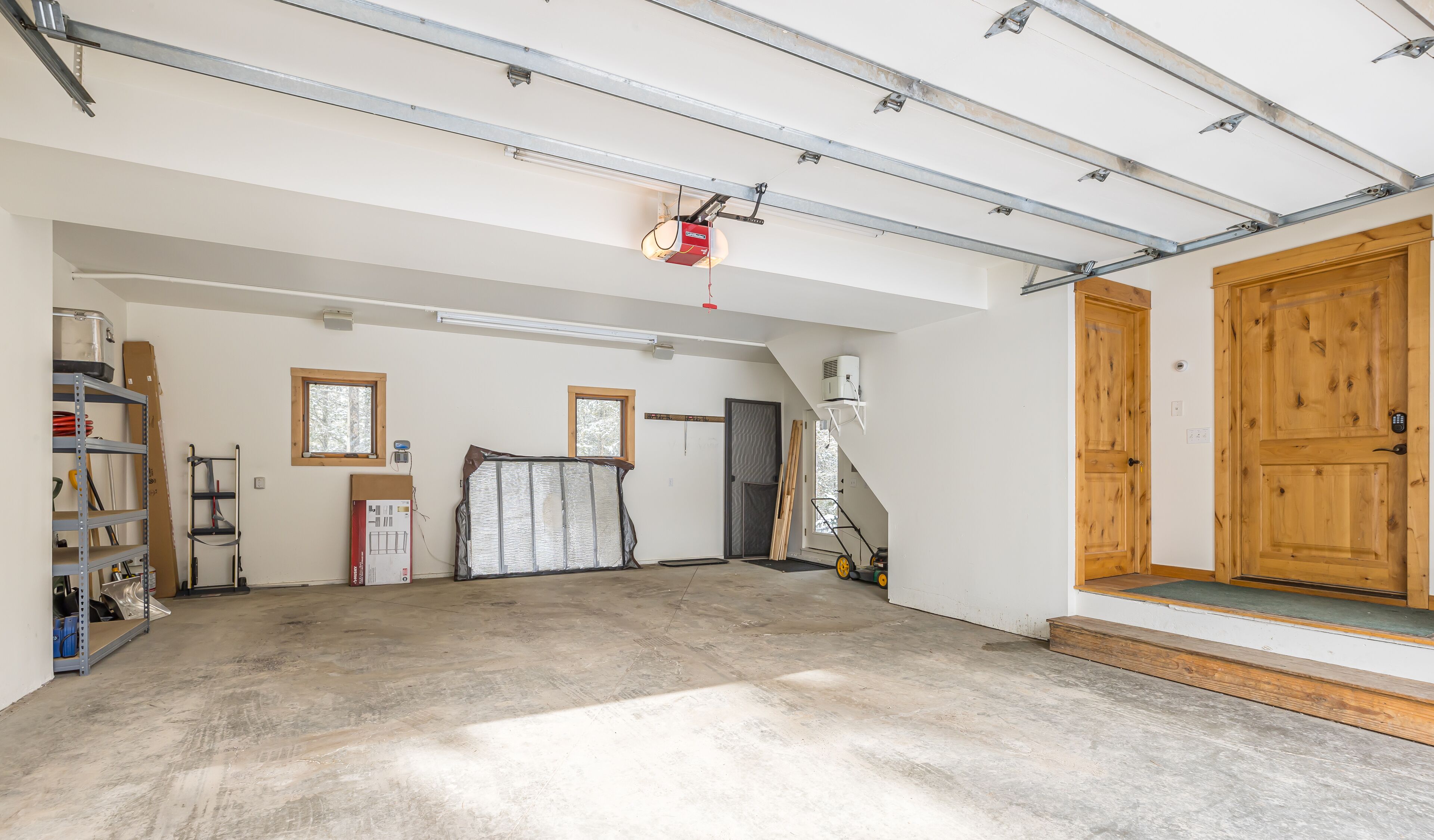 A spacious garage with a concrete floor, wooden door, and metal beams on the ceiling.