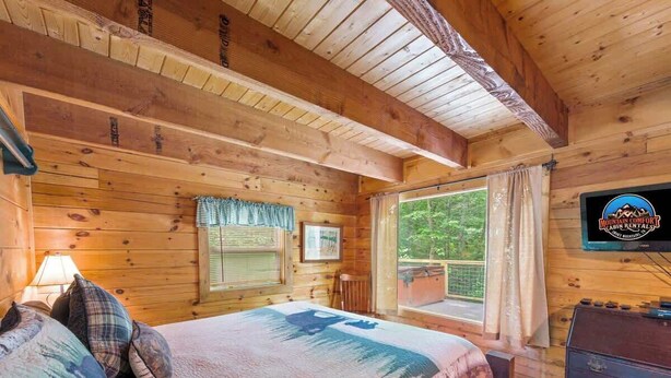 Une chambre de cabane comprenant un lit, une fenêtre, une commode et une enseigne indiquant « Mountain Comfort Cabin Rentals ».
