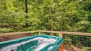 Un bain à remous sur une terrasse en bois, entouré d’une végétation luxuriante.