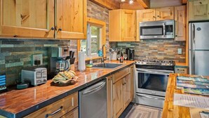 Una cocina moderna con armarios de madera, un microondas de acero inoxidable, una estufa a gas y un horno empotrado.