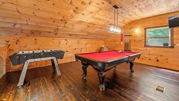 Una sala con paneles de madera, mesa de billar y mesa de futbolín.