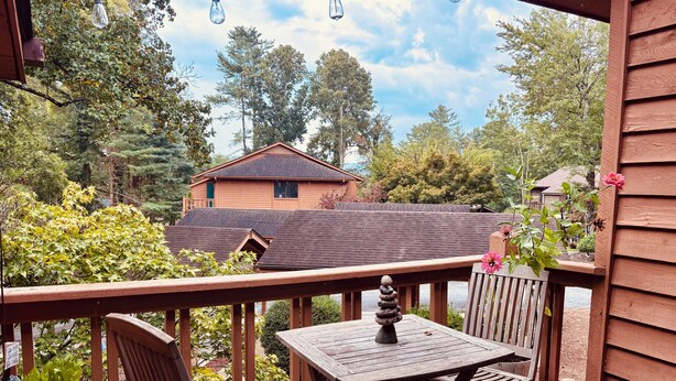 Une terrasse en bois avec une table et des chaises, donnant sur un quartier résidentiel avec des maisons et des arbres.