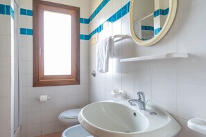 A bathroom with a toilet, sink, and a window.