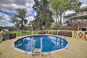 Une piscine dotée d’une terrasse en bois, entourée d’une clôture en bois et d’un espace de terrasse couvert.