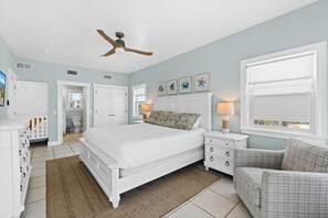 A bedroom with a bed, nightstands, a chair, a ceiling fan, and a window.