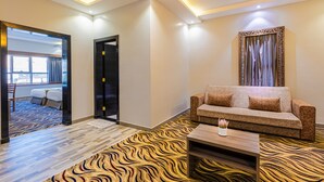 A modern hotel room with a sofa, a coffee table, and a patterned carpet. - Luma Serviced Apartments (Madinah)