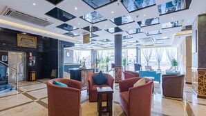A spacious lobby with a checkered floor, multiple seating areas, and a large pillar. - Luma Serviced Apartments (Madinah)