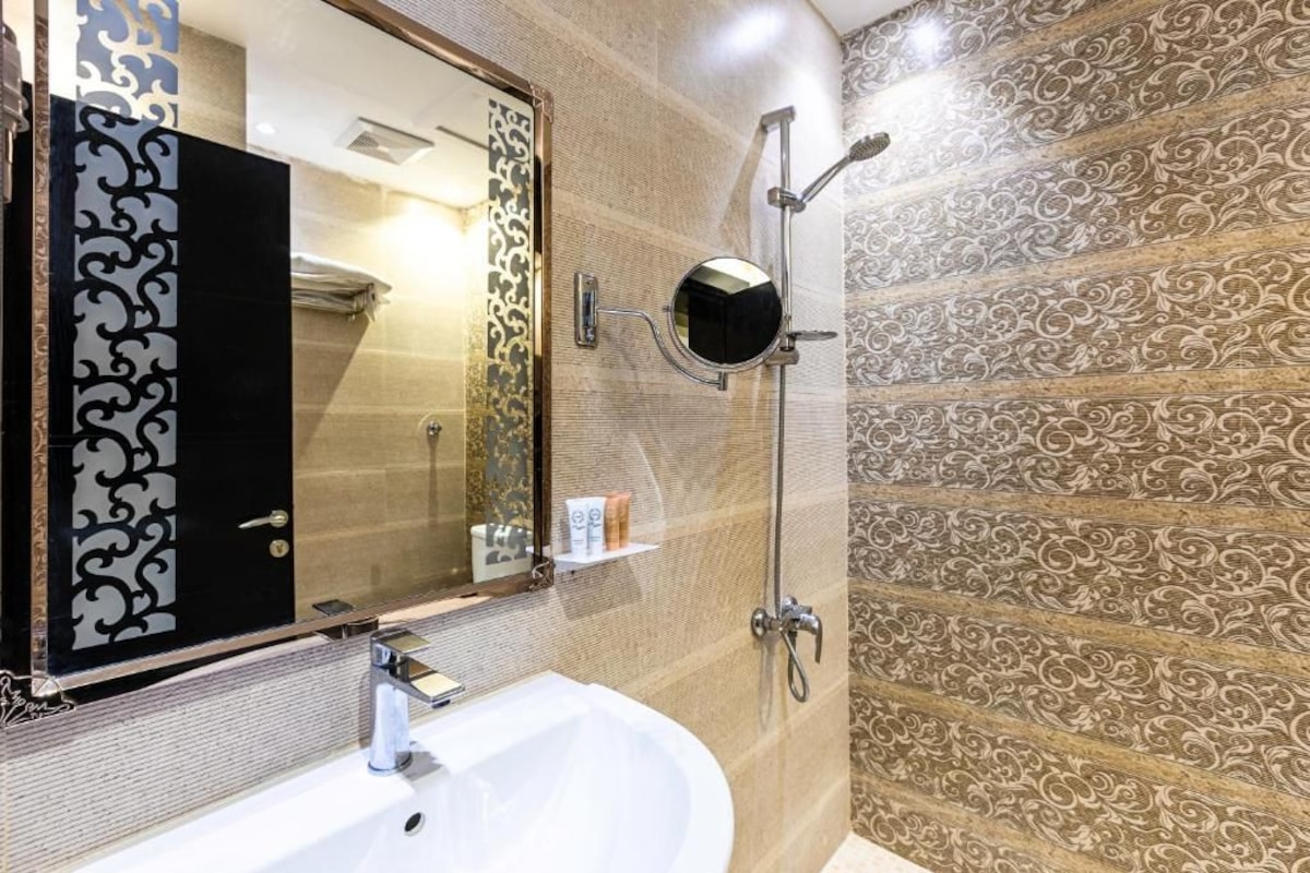 A bathroom with a white sink, a mirror, and a shower with a handheld showerhead.