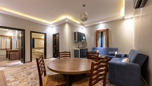 A modern hotel room with a dining area, a sofa, a cabinet, and a patterned carpet. - Luma Serviced Apartments (Madinah)