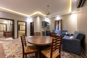 A modern hotel room with a dining area, a sofa, a cabinet, and a patterned carpet. - Luma Serviced Apartments (Madinah)